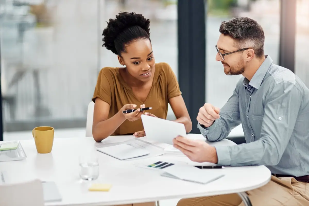 A man and a woman having a meeting at a table with documents on the table